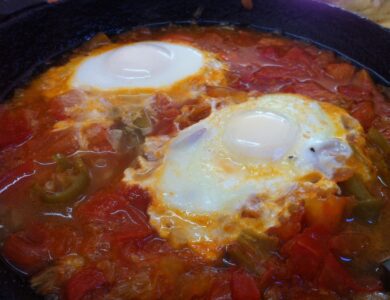 Shakshuka mit pochierten Eiern in würziger Tomaten-Paprika-Sauce in einer Pfanne