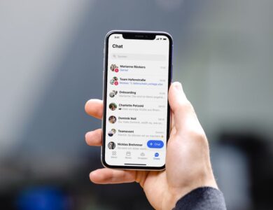 Hand hält ein Smartphone mit geöffneter Chat-Übersicht.